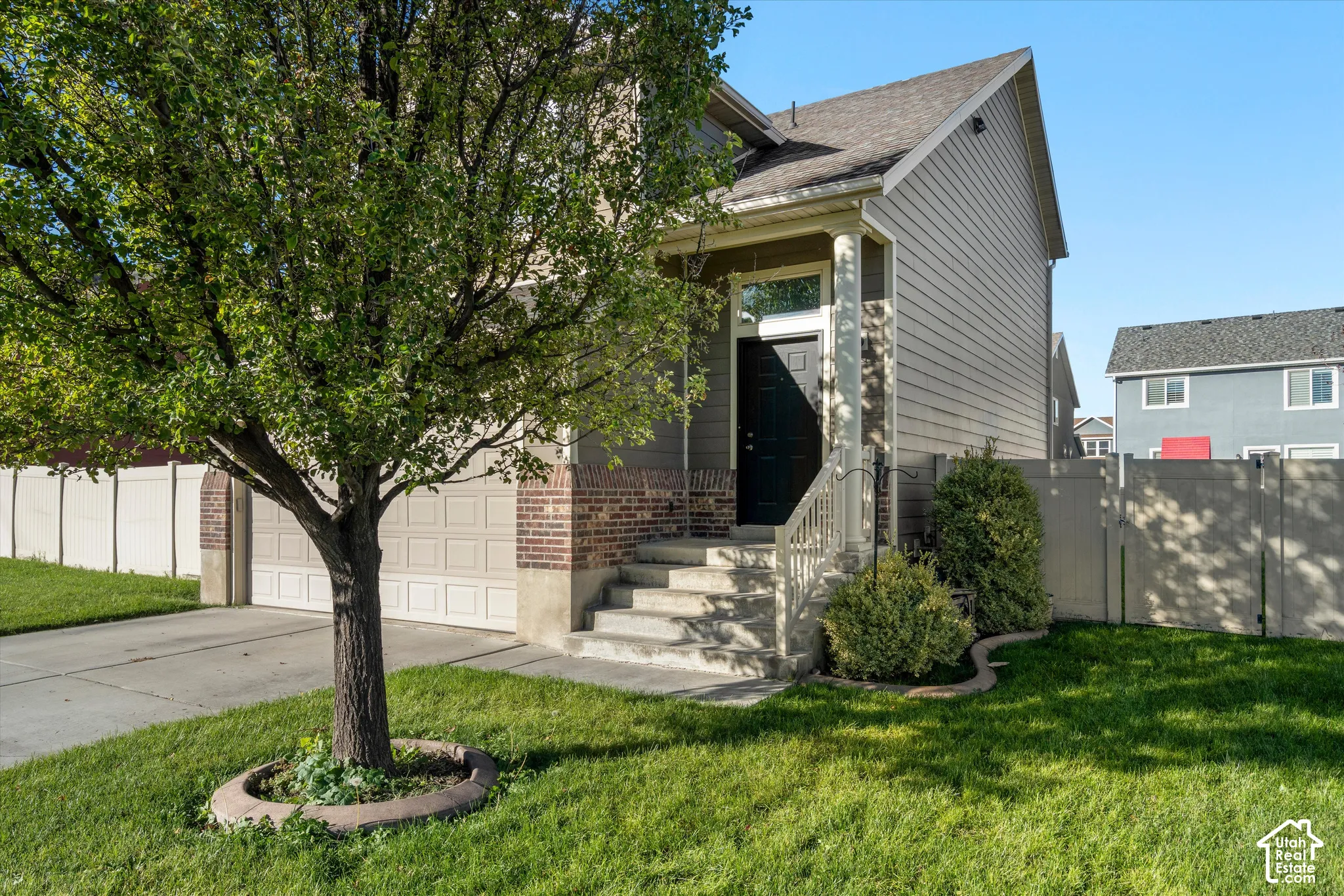 Two-story residence featuring horizontal siding, a brick facade accent, covered entryway with a column, and a concrete driveway