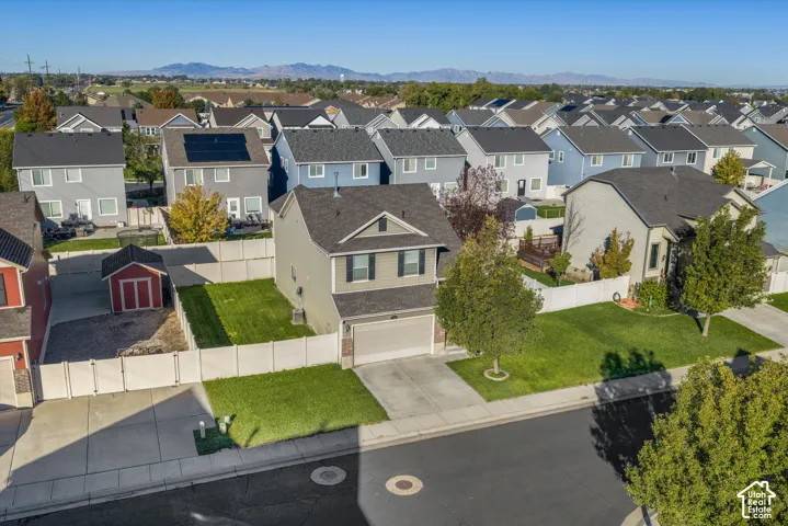 Two-story residence featuring a shingled roof, attached two-car garage, fenced yard, and mountain backdrop