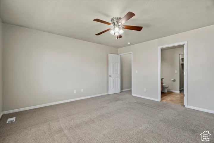 Neutral interior featuring wall-to-wall carpeting, a multi-blade ceiling fan with integrated lighting, and a six-panel interior door