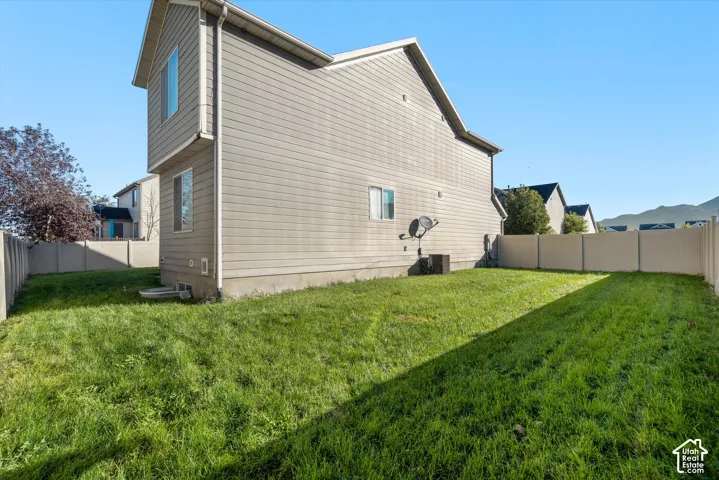 Side yard featuring horizontal siding, a fenced perimeter, and an open grass area
