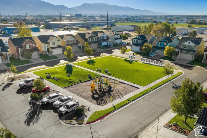 Community park area featuring open green space, mature landscaping, and a playground installation against a mountain backdrop