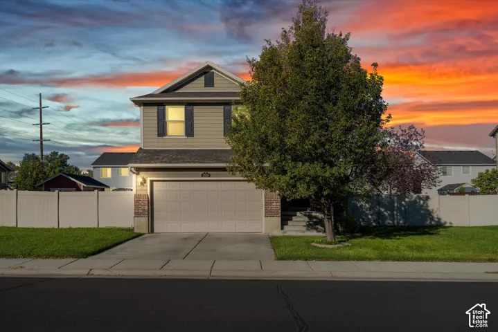 Two-story residence featuring horizontal siding, brick accents, an attached two-car garage, and a full-perimeter privacy fence