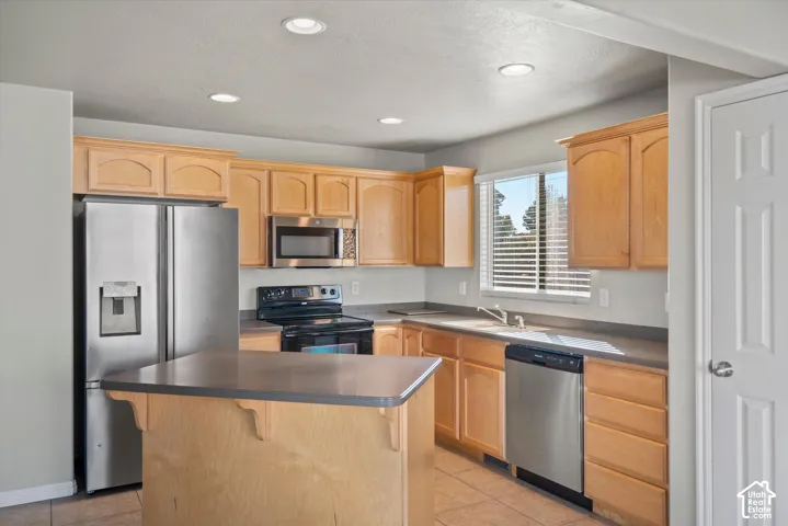 Kitchen featuring wood cabinetry, stainless steel appliances, a center island with a stone-finish countertop, and recessed lighting