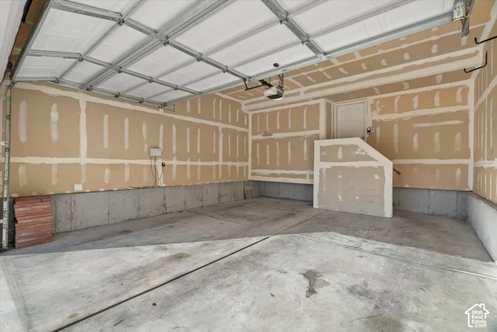 Multi-car garage featuring a concrete floor, sectional overhead door, and unfinished drywall walls