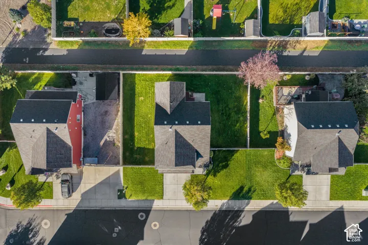 Aerial perspective of a residential lot featuring a manicured lawn, concrete driveway, and full perimeter fencing