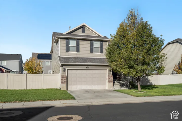 Two-story exterior featuring horizontal siding, decorative brick accents, asphalt shingle roofing, and an attached two-car garage