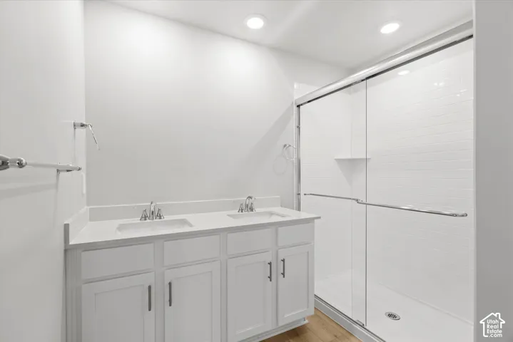 Dual-sink vanity with a solid-surface countertop, white shaker-style cabinetry, walk-in shower with a glass enclosure, and white subway tile wall surround