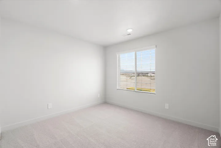 Neutral-toned interior room with high-pile wall-to-wall carpeting, window with integrated blinds, and recessed lighting