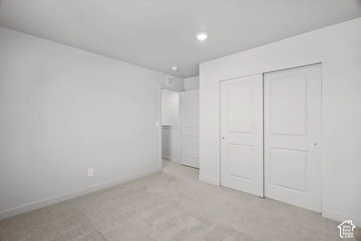 Neutral-toned carpeting, recessed ceiling lighting, and white paneled sliding closet doors