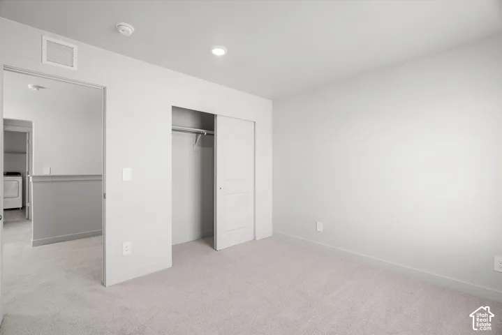 Neutral-toned interior featuring wall-to-wall carpeting, recessed lighting, and a closet with a sliding panel door