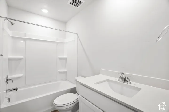 Bathroom featuring a composite surround tub-shower combination, vanity with an integrated basin, chrome finish hardware, and recessed ceiling lighting