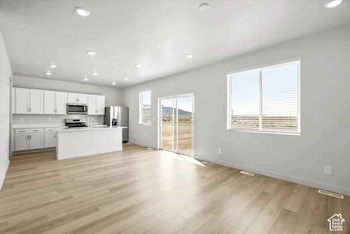 Kitchen featuring white shaker-style cabinetry, a quartz countertop island, recessed lighting, and wood-finish flooring