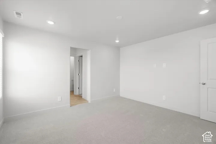 Neutral interior space featuring recessed ceiling lighting, wall-to-wall carpeting, and a multi-panel interior door