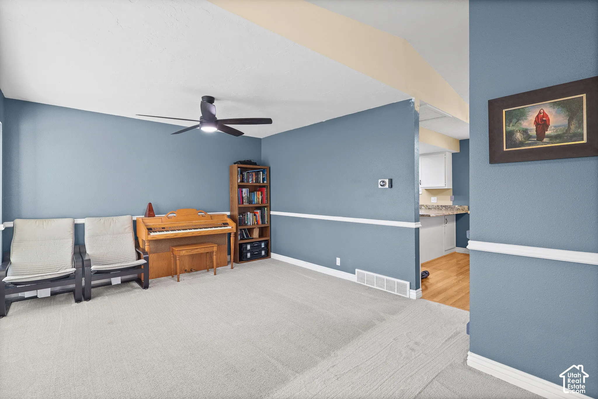 Vaulted ceiling with an attached multi-blade ceiling fan, wall-mounted chair rail molding, and neutral wall tones