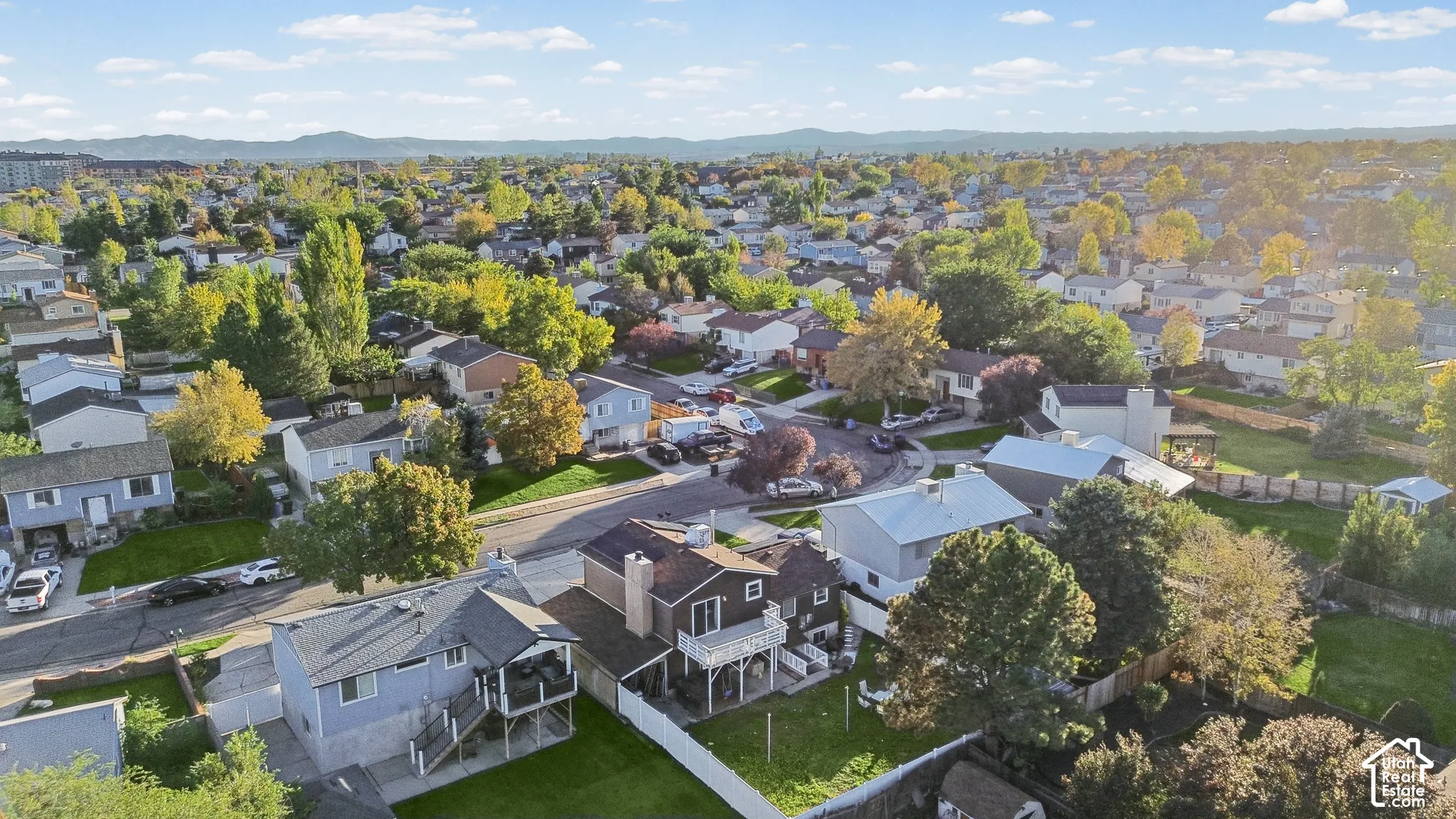 Aerial perspective of a suburban neighborhood featuring mature trees, residential street layouts, and a distant mountain backdrop