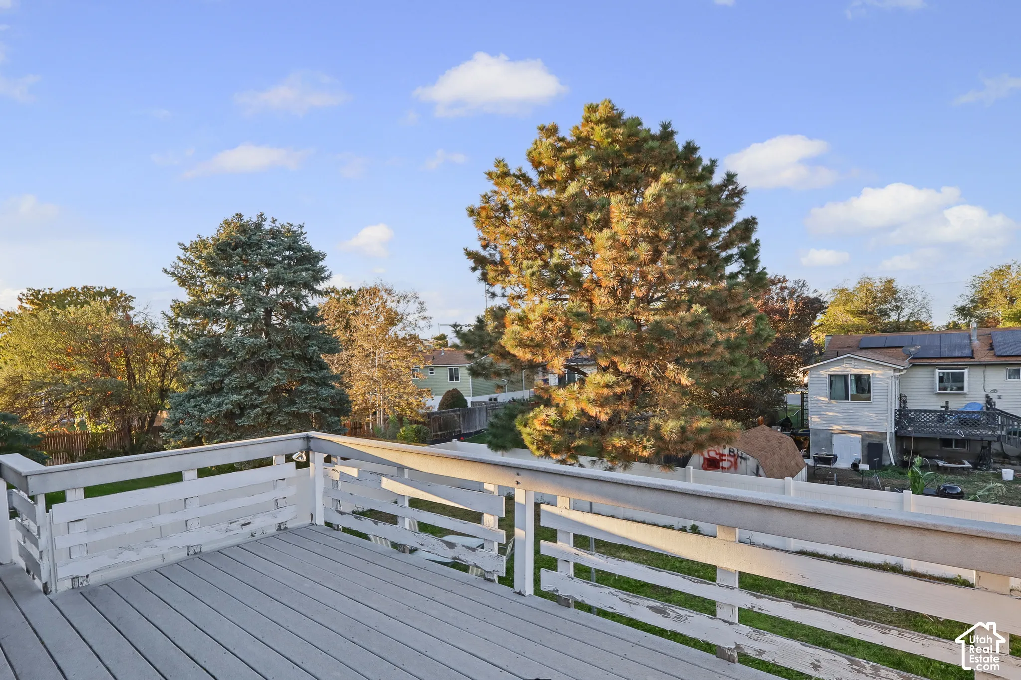 Elevated wooden deck with horizontal rail fencing, mature trees, and open-air layout