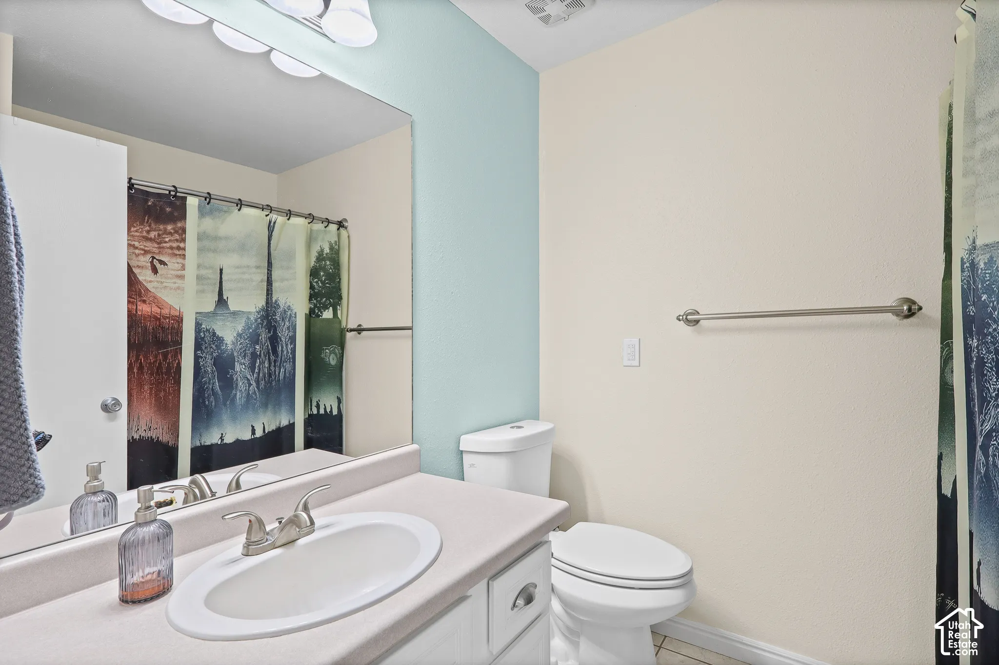 Bathroom featuring a vanity with a white integrated oval sink, chrome two-handle faucet, full-width wall mirror, multi-light fixture, and ceramic toilet