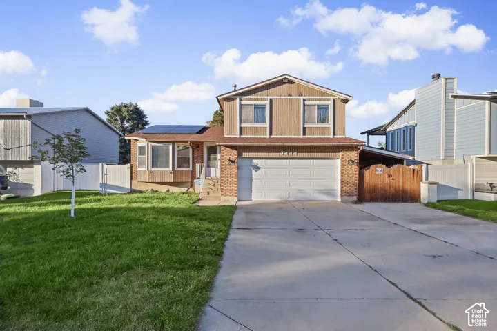 Split-level exterior featuring brick masonry, vertical siding, solar panels, a two-car garage, and a concrete driveway