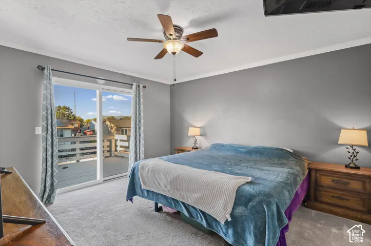 Main bedroom featuring neutral wall paint, carpeted flooring, a ceiling fan with integrated lighting, and sliding glass doors leading to an exterior balcony