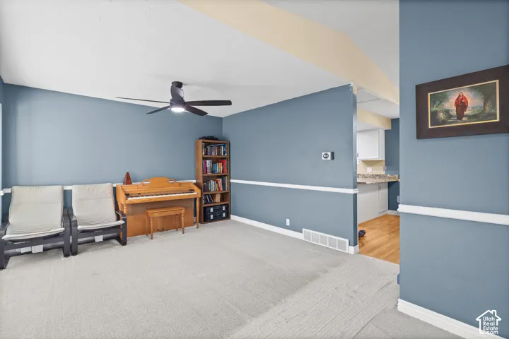 Vaulted ceiling with an attached multi-blade ceiling fan, wall-mounted chair rail molding, and neutral wall tones