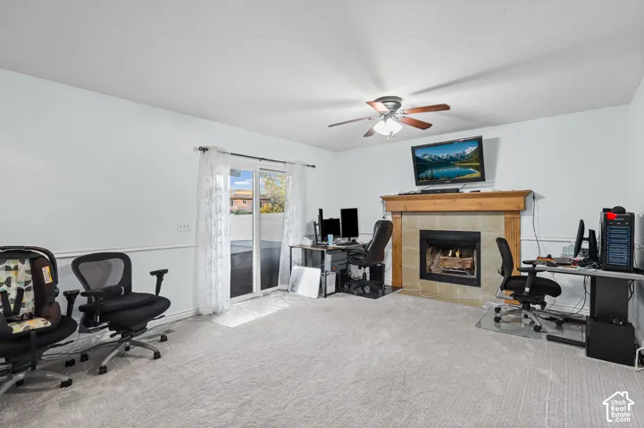 Fireplace in family room featuring a stone surround and wood mantel, sliding glass door, and a ceiling fan with integrated lighting
