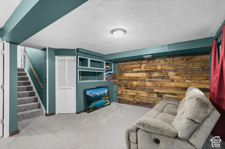 Accent wall with reclaimed wood planking, built-in shelving, carpeted stairs with a wooden handrail, and louvered closet doors