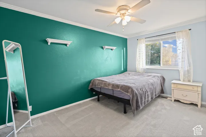 Bedroom featuring neutral carpeting, dual wall-mounted shelving, a ceiling fan with integrated lighting, and a large window