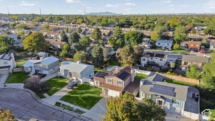 Aerial perspective featuring two-story residences with asphalt shingle roofing, integrated rooftop solar arrays, manicured lawns, and concrete driveways