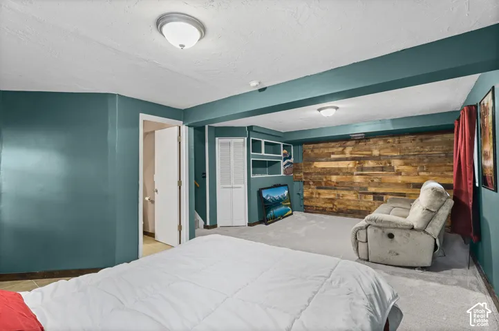 Interior space featuring a reclaimed wood accent wall, recessed shelving, built-in bi-fold closet, and dual flush-mount light fixtures