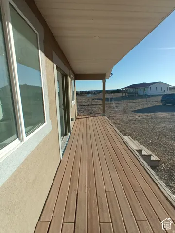 Covered exterior deck featuring composite decking, neutral-toned stucco siding, and large glass windows