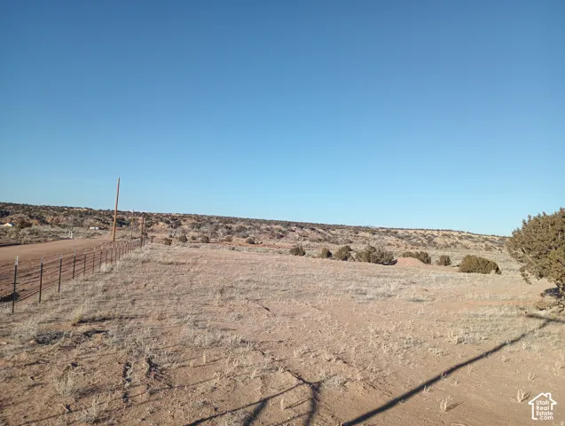 Expansive desert acreage featuring native vegetation, dirt road access, and perimeter wire fencing