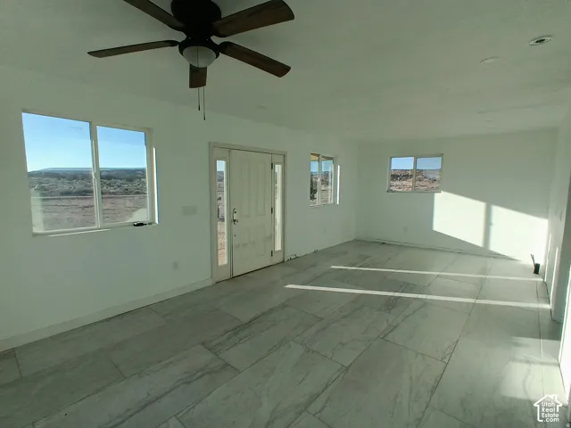 Interior space featuring large-format tile flooring, recessed lighting, a ceiling fan, and a multi-panel entry door with sidelights