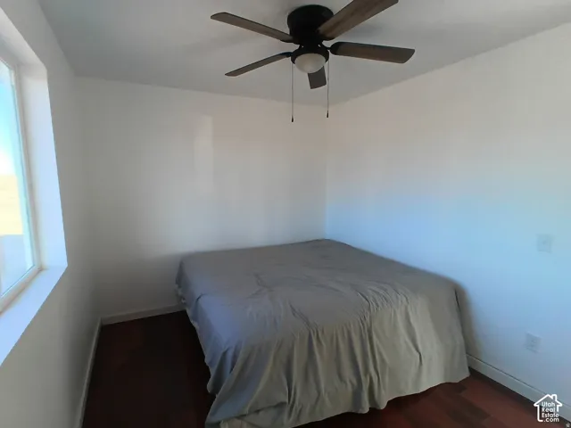 Bedroom featuring wood-finish flooring, a neutral wall color palette, and a central ceiling fan with integrated lighting