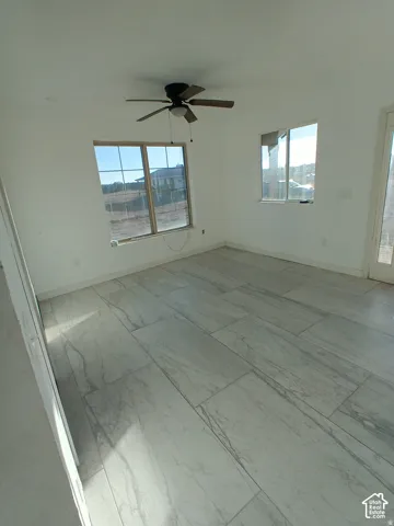Large-format stone-pattern tile flooring, multi-pane windows, and ceiling-mounted light fixture with fan
