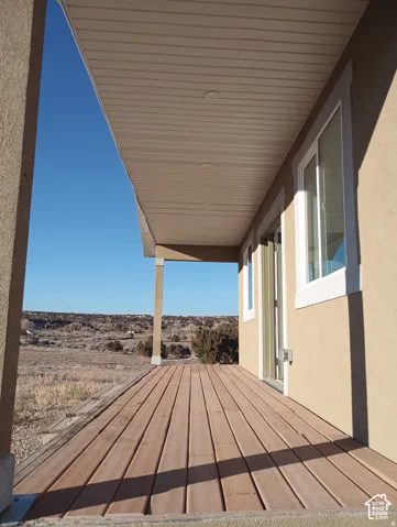 Covered exterior porch featuring wood-finish decking, recessed ceiling lighting, stucco siding, and double-pane vinyl windows