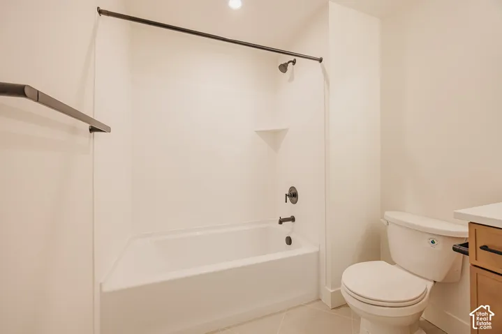 Bathroom featuring a tub-shower combination with matte black fixtures, built-in shelving, a light-toned vanity, and tile flooring
