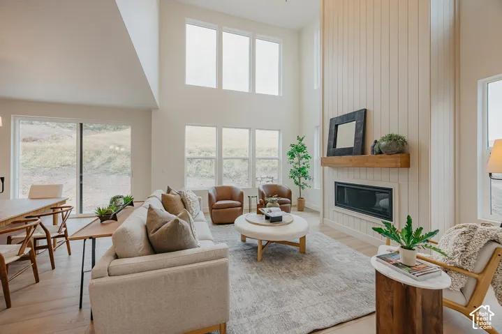 Double-height ceiling, floor-to-ceiling vertical plank fireplace surround, linear gas insert, wood-finish mantel, and expansive windows
