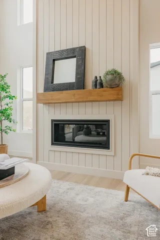 Floor-to-ceiling vertical plank paneling accent wall featuring a linear fireplace with a natural-finish wood beam mantel