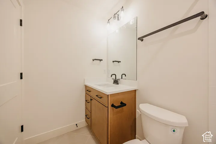 Vanity featuring a light wood finish, white countertop, matte black hardware, and integrated sink