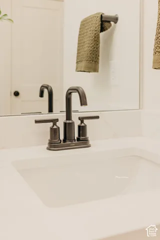 Stone-surfaced countertop with an integrated rectangular undermount sink, complemented by a matte black widespread faucet and matching wall-mounted towel bar