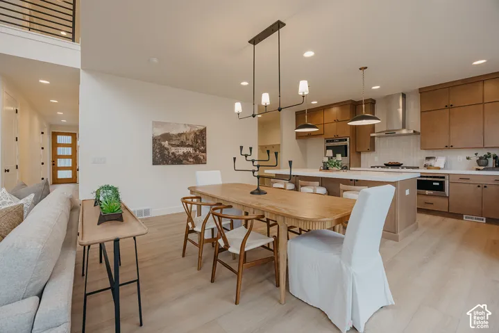 Kitchen featuring flat-panel wood cabinetry, a central island with countertop seating, integrated stainless steel appliances, and wood-finish flooring