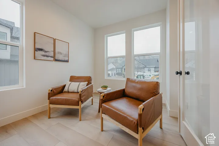Bright room featuring wood-finish flooring, tall dual-pane windows, and a glass-panel door with matte black hardware