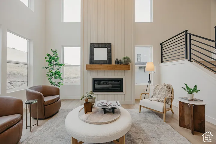 Double-height ceiling, floor-to-ceiling vertical shiplap fireplace surround, built-in horizontal wood mantel, oversized windows, and modern metal stair railing