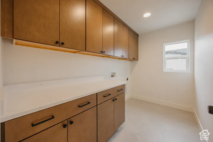 Custom cabinetry featuring wood-finish upper and lower storage, stone-surface countertop, integrated hardware, and large-format tile flooring