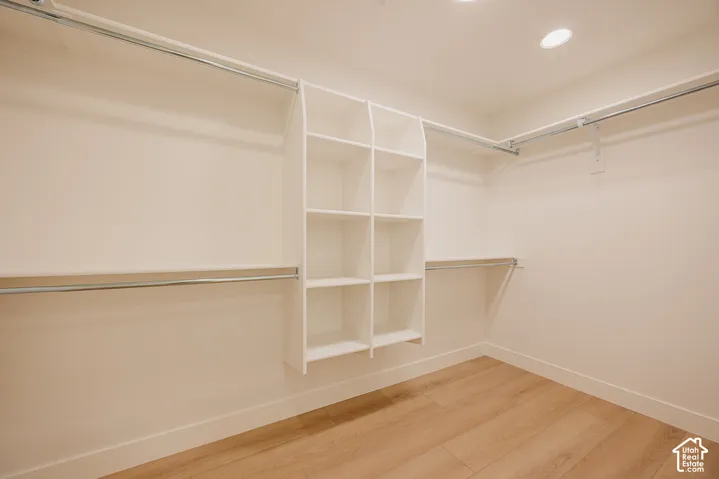 Walk-in closet featuring wood-finish flooring, built-in shelving towers, and dual-level hanging rods