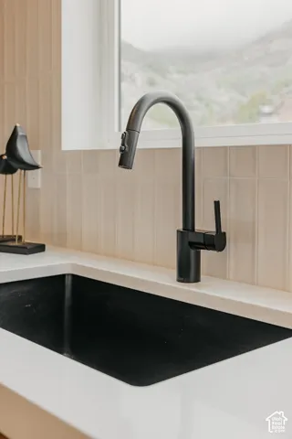 Matte black gooseneck pull-down faucet paired with a deep integrated basin, quartz countertop, and vertical tile backsplash
