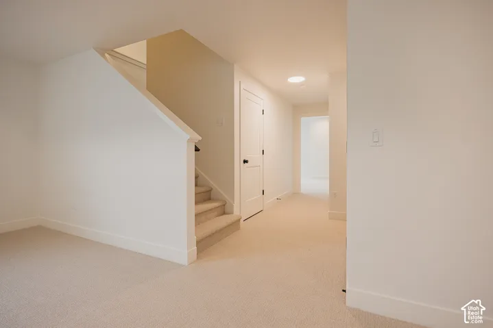 Interior featuring neutral wall-to-wall carpeting, staircase with a handrail, solid-core panel door with matte black hardware, and a recessed ceiling light