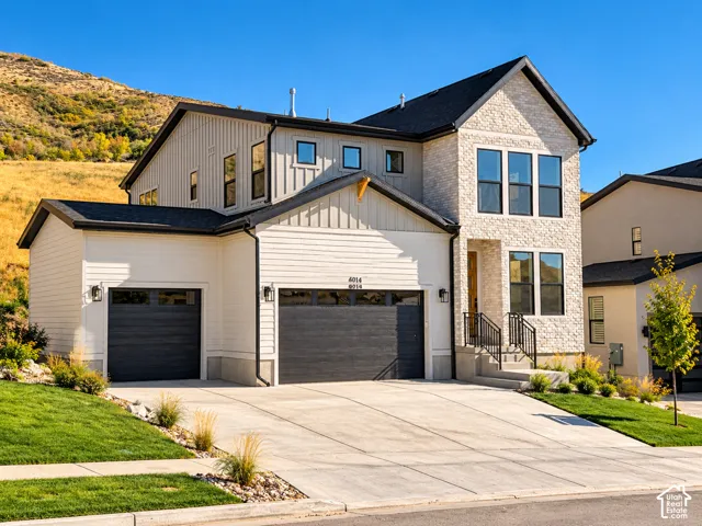Multi-level residence featuring a composite stone and vertical siding exterior, three-car garage with dark-finish doors, and concrete driveway