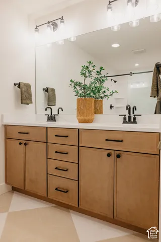 Double vanity featuring light-tone wood cabinetry, white countertops, matte black hardware, and an expansive wall-to-wall mirror