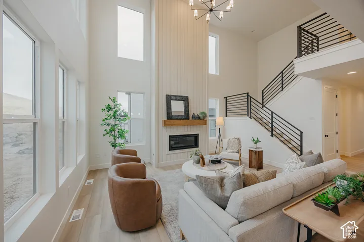 Double-height ceiling, vertical shiplap fireplace surround with a natural wood mantel, wood-finish flooring, and black metal staircase railing